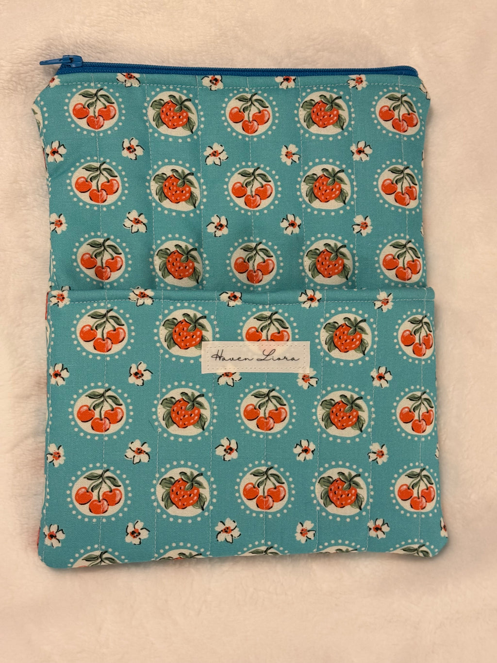 Sweet Cherry Pie Blue Kindle Sleeve exterior in sky blue strawberry and cherry print with front pocket and size comparison