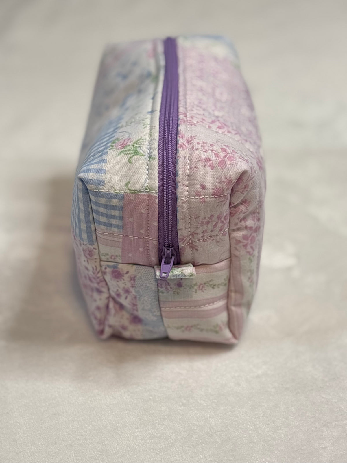 Side view of Lilac and Lace makeup bag showing purple zipper